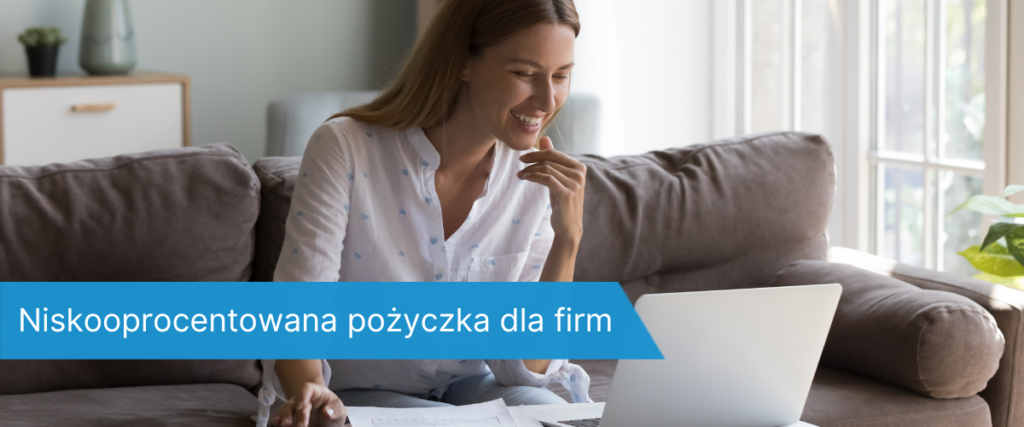 Uśmiechnięta kobieta siedząca na kanapie z laptopem i dokumentami, analizująca ofertę pożyczki